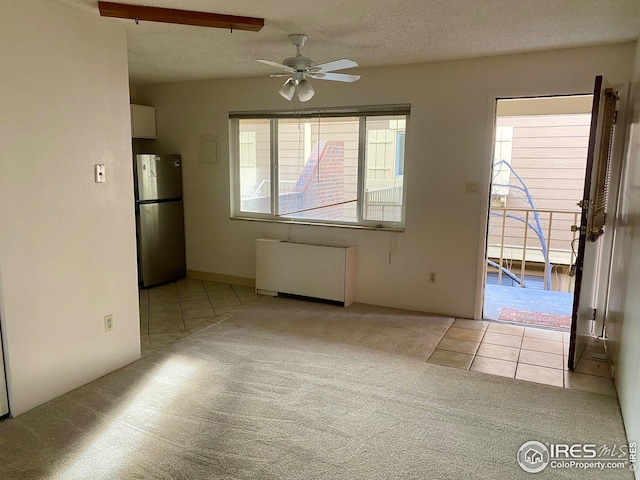 unfurnished dining area featuring carpet floors, a textured ceiling, ceiling fan, and radiator heating unit