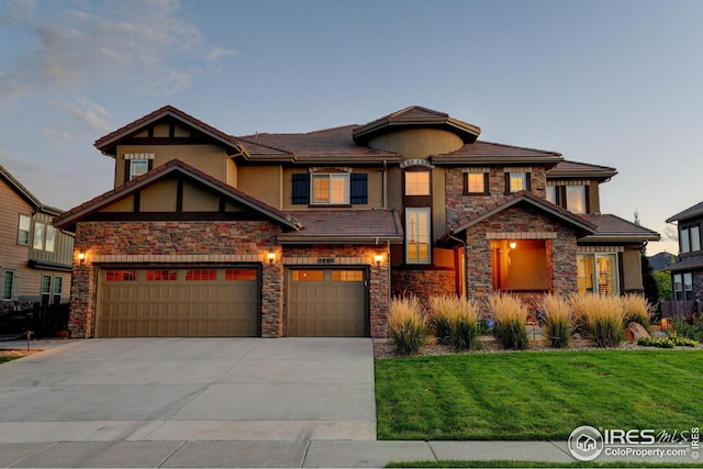 view of front of home featuring a front lawn, a tile roof, stucco siding, stone siding, and driveway