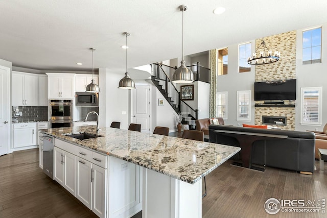 kitchen featuring a sink, decorative backsplash, appliances with stainless steel finishes, white cabinetry, and open floor plan