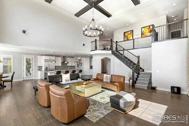 living room featuring baseboards, a notable chandelier, stairs, and dark wood-type flooring