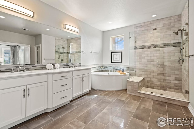 full bath featuring tile patterned flooring, a shower stall, a garden tub, double vanity, and a sink