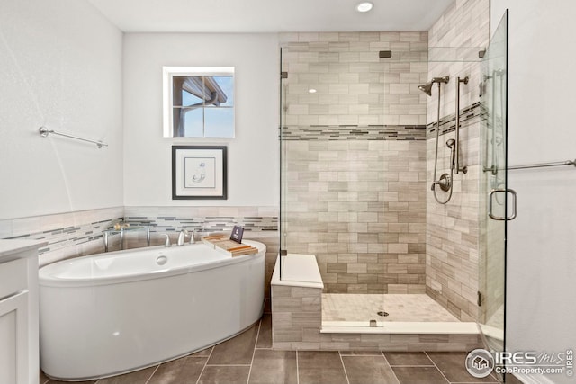 bathroom with tile patterned floors, a freestanding tub, tile walls, and a stall shower