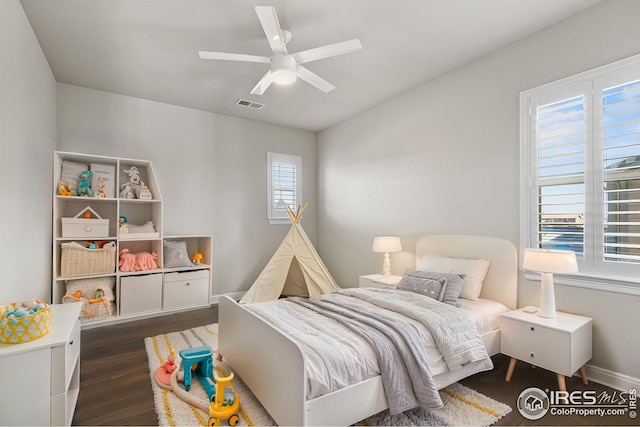 bedroom with dark wood-style floors, visible vents, and ceiling fan