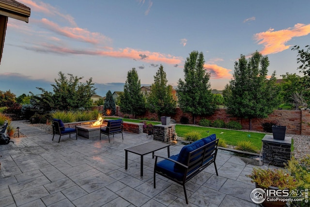 patio terrace at dusk featuring a fire pit and a lawn