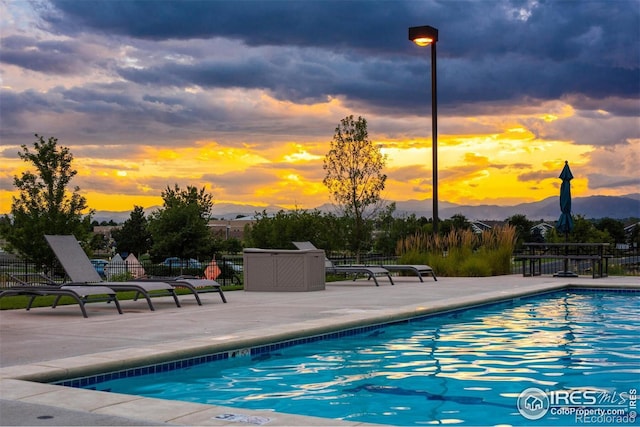 community pool with a patio area, fence, and a mountain view