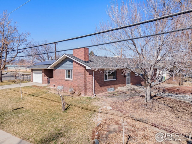 view of front of home featuring solar panels, a chimney, concrete driveway, a garage, and brick siding