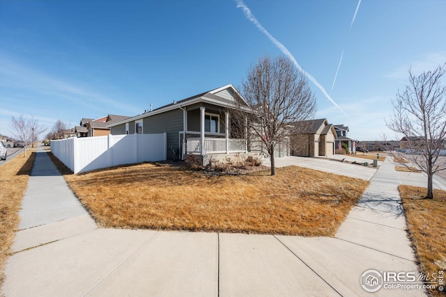 view of front of property with a residential view, covered porch, driveway, and fence