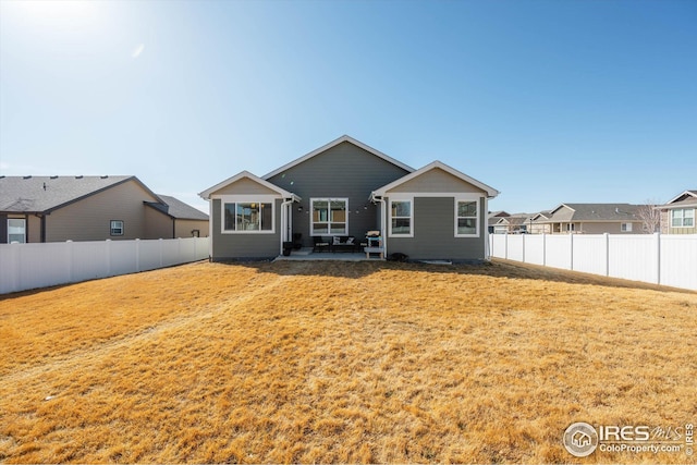 rear view of house with a patio, a yard, and a fenced backyard