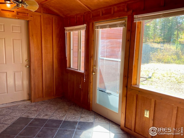 doorway to outside featuring wood walls and a ceiling fan