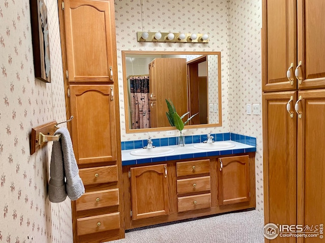 full bathroom featuring a sink, double vanity, and wallpapered walls