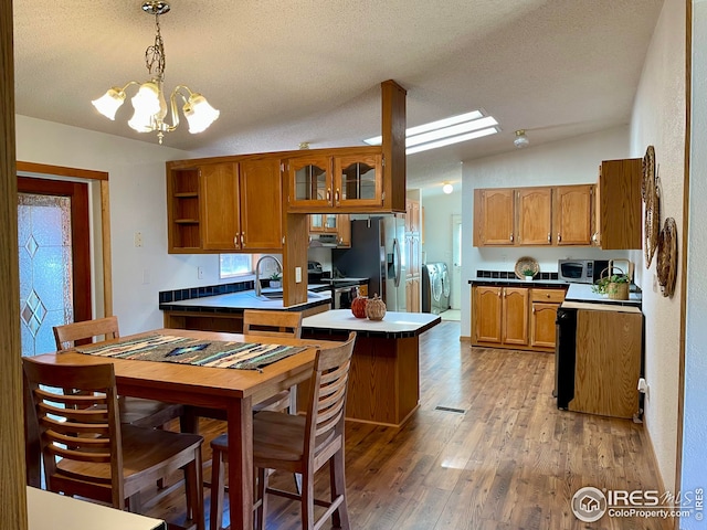 kitchen featuring brown cabinets, appliances with stainless steel finishes, a peninsula, and washer and clothes dryer