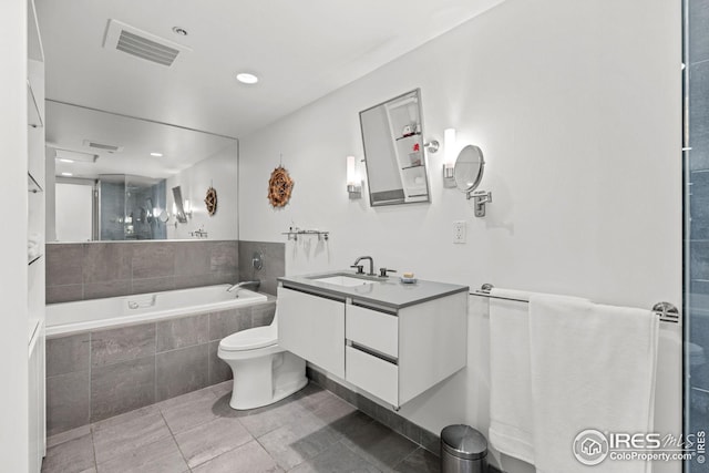bathroom with visible vents, toilet, vanity, and a garden tub
