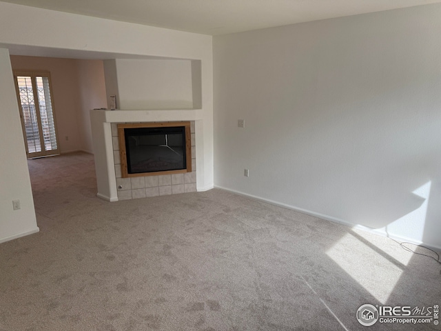 unfurnished living room with a tiled fireplace and carpet