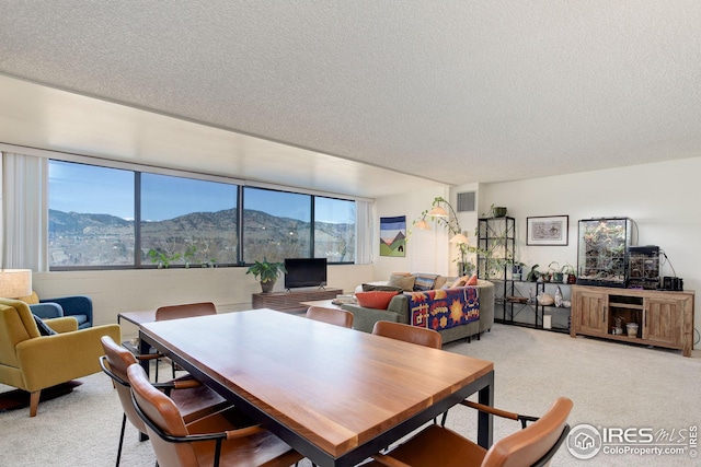 dining room featuring light carpet, visible vents, a healthy amount of sunlight, and a textured ceiling