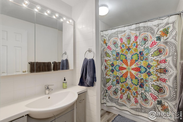 bathroom featuring vanity, curtained shower, wood finished floors, and backsplash