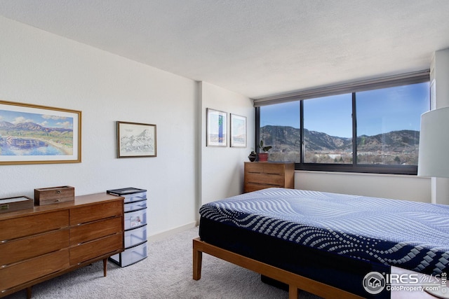 carpeted bedroom with a mountain view, baseboards, and a textured ceiling