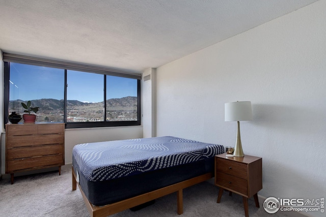 bedroom with visible vents, a mountain view, a textured ceiling, and carpet