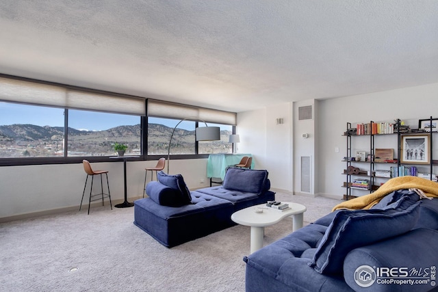 living room with a mountain view, carpet, visible vents, and a textured ceiling