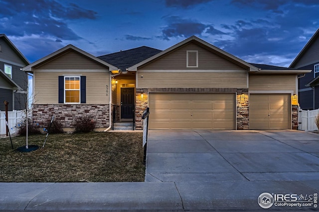 view of front of property featuring stone siding, an attached garage, and fence