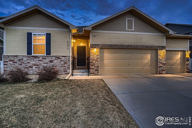 view of front of house with stone siding, driveway, and a garage