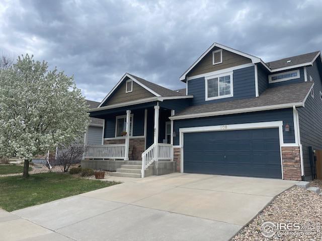 craftsman inspired home with stone siding, covered porch, and concrete driveway