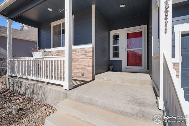 property entrance with covered porch and stone siding