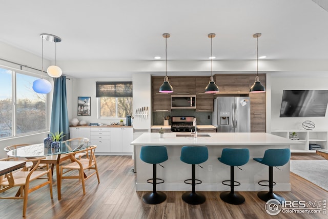 kitchen featuring light wood-style flooring, stainless steel appliances, light countertops, and a breakfast bar area