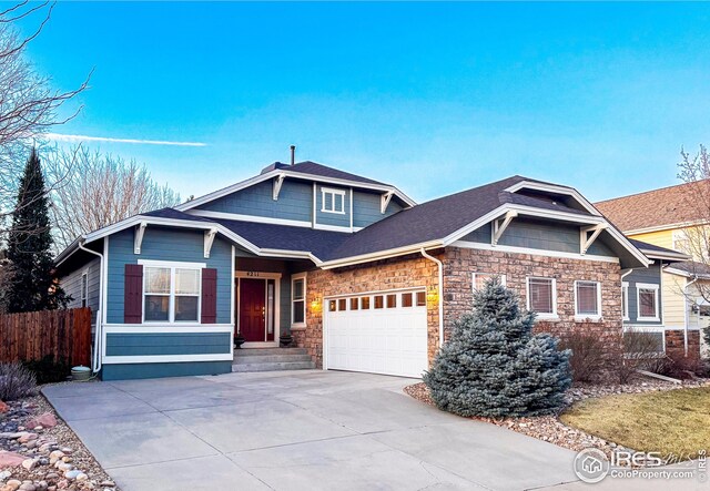 view of front facade featuring fence, roof with shingles, concrete driveway, a garage, and stone siding