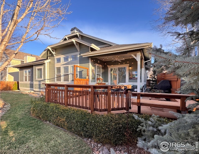 back of house with a wooden deck, a yard, a ceiling fan, and a shingled roof