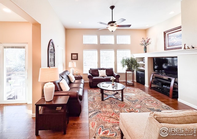 living area featuring baseboards, a ceiling fan, and wood finished floors