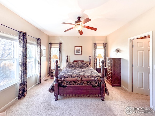 bedroom with multiple windows, baseboards, and light carpet