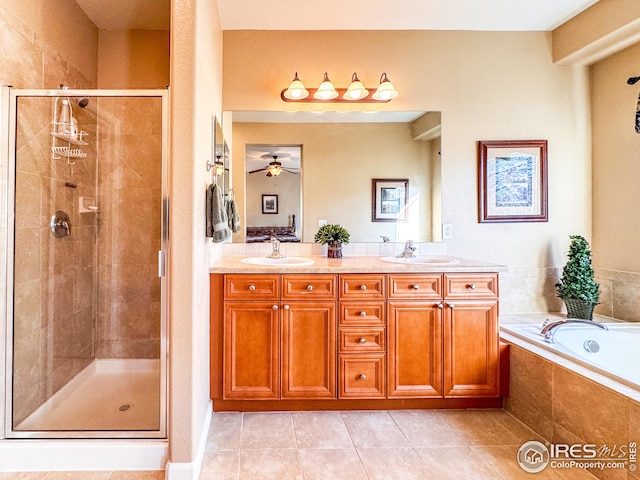 full bathroom featuring a ceiling fan, double vanity, a sink, a shower stall, and a garden tub