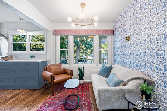 living area featuring a wealth of natural light, wood finished floors, and a chandelier