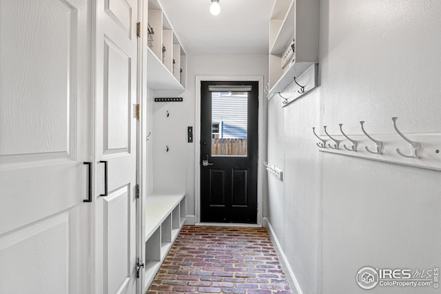 mudroom with baseboards and brick floor