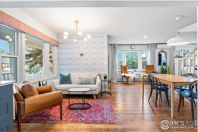 interior space featuring a wall mounted air conditioner, an accent wall, an inviting chandelier, and wood finished floors