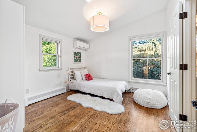 bedroom featuring a baseboard heating unit, lofted ceiling, a wall unit AC, and wood finished floors