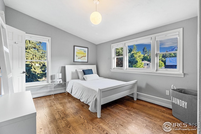 bedroom with baseboards, multiple windows, wood finished floors, and vaulted ceiling