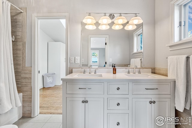 full bathroom with double vanity, tile patterned floors, a tile shower, and a sink