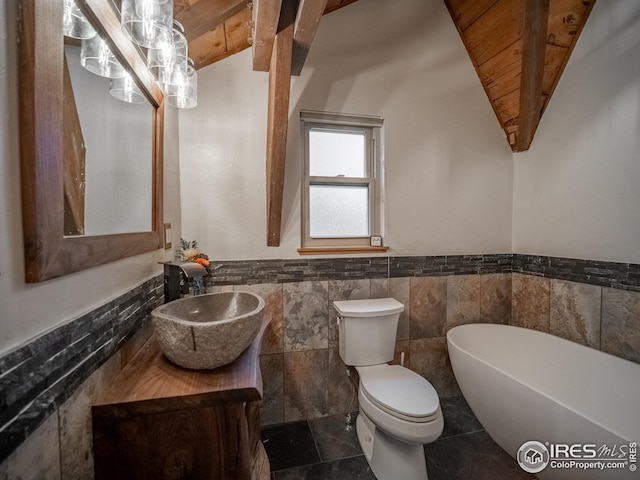 full bathroom featuring a wainscoted wall, toilet, a freestanding bath, vanity, and vaulted ceiling