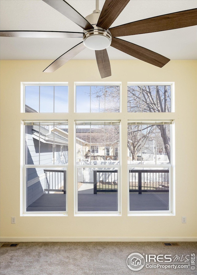 interior space featuring carpet flooring, visible vents, baseboards, and ceiling fan