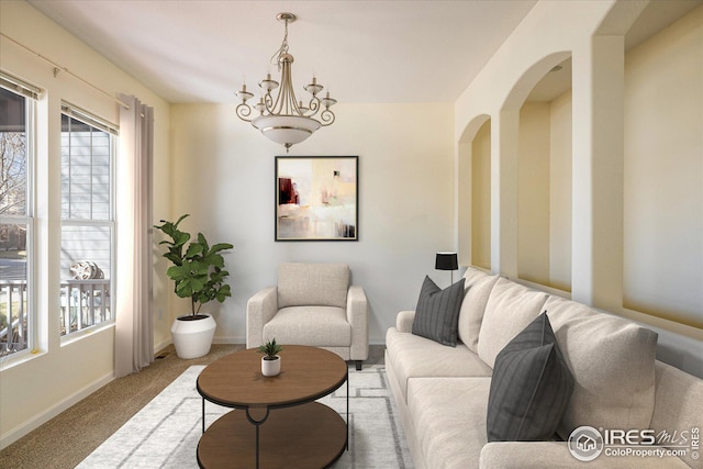 living area with arched walkways, baseboards, and carpet floors