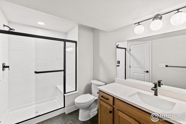 bathroom with tile patterned flooring, toilet, vanity, and a tile shower
