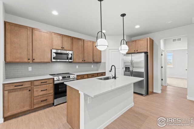 kitchen with visible vents, light wood-type flooring, decorative backsplash, stainless steel appliances, and a sink