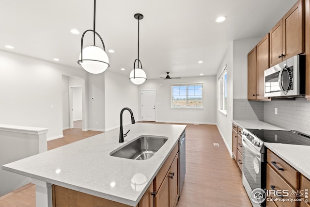 kitchen featuring tasteful backsplash, ceiling fan, brown cabinetry, stainless steel appliances, and a sink