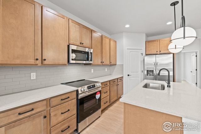 kitchen featuring pendant lighting, a center island with sink, a sink, stainless steel appliances, and decorative backsplash
