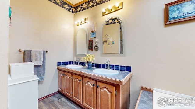 full bath with baseboards, wood finished floors, a sink, and double vanity