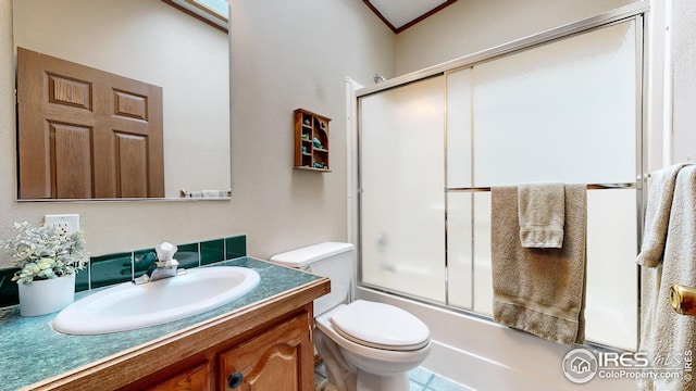 bathroom featuring crown molding, combined bath / shower with glass door, vanity, and toilet