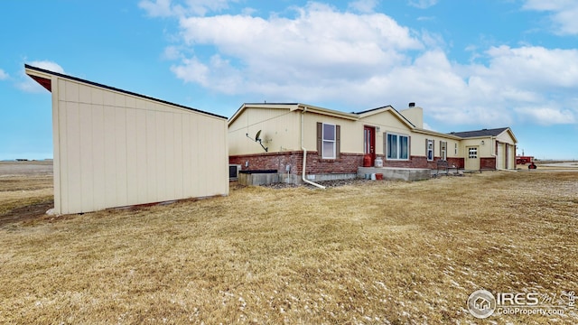 exterior space featuring a chimney, a front lawn, and brick siding