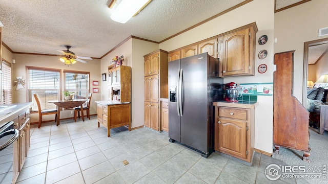kitchen with stainless steel fridge, a ceiling fan, brown cabinets, light countertops, and ornamental molding