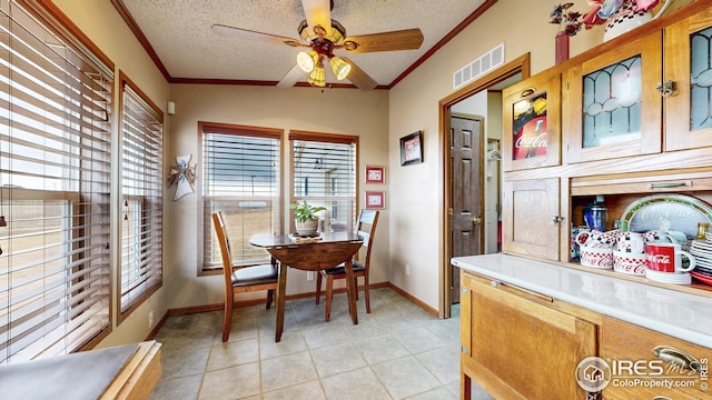 dining room featuring crown molding, a textured ceiling, ceiling fan, baseboards, and visible vents